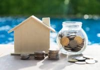 Business loans for real estate concept, a money bags put in a model home on the table on bokeh background in the public park.